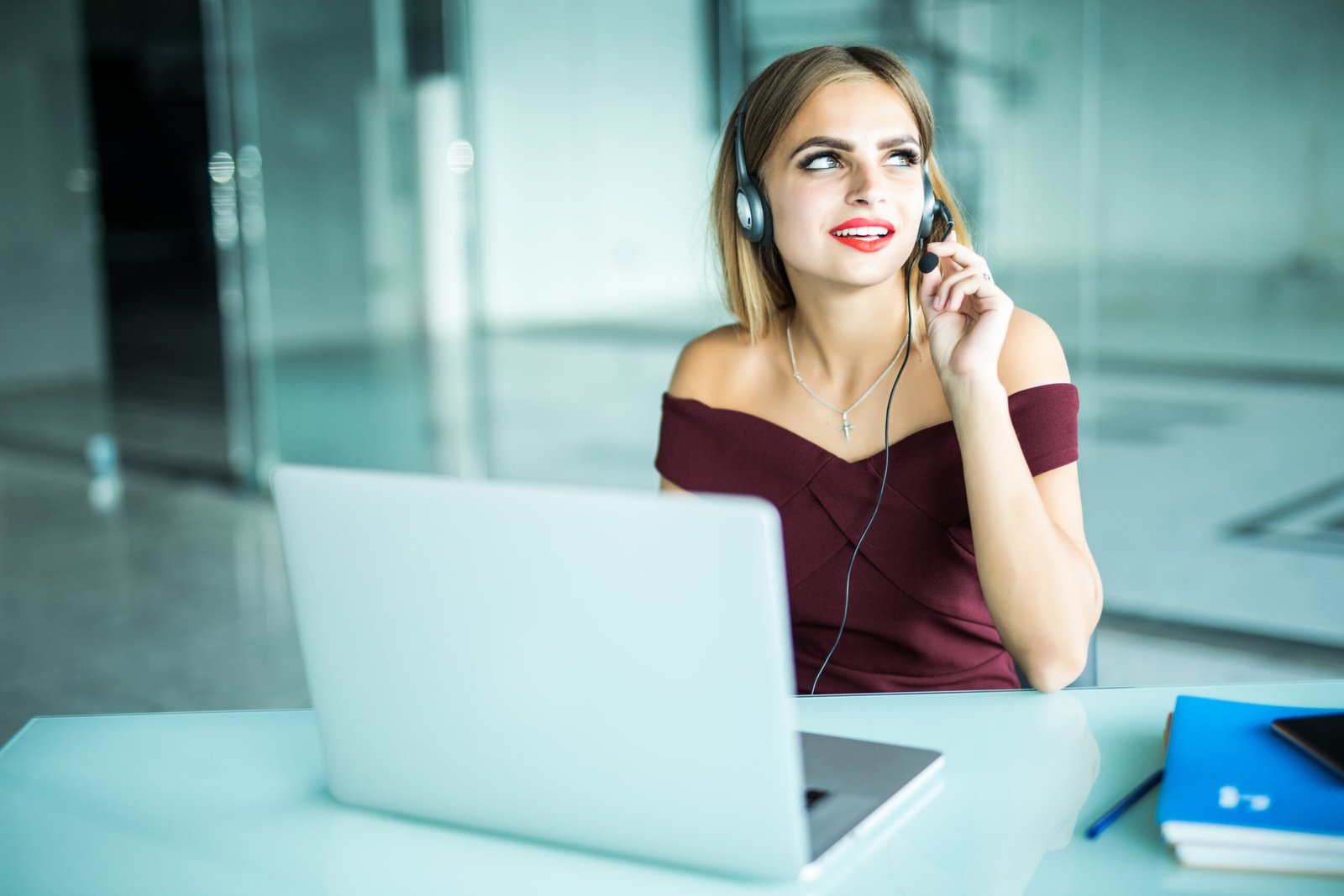 Focused woman in headphones sits at desk with laptop, looks at screen, makes notes, learns foreign language in internet, online study course, self-education on web, consults client by video